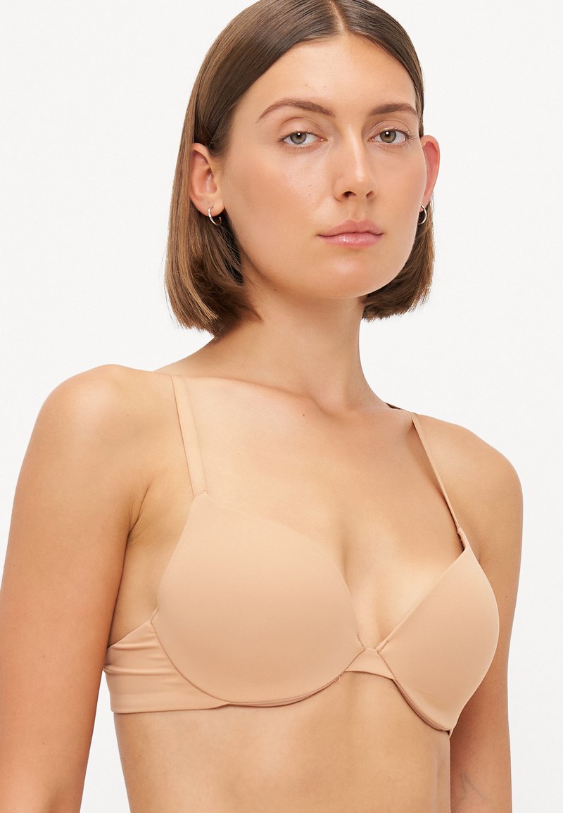 Jasnobeżowy biustonosz push-up z formowanymi, bezszwowymi miseczkami, regulowanymi ramiączkami oraz gładką, miękką fakturą. Prosty design bez zdobień.