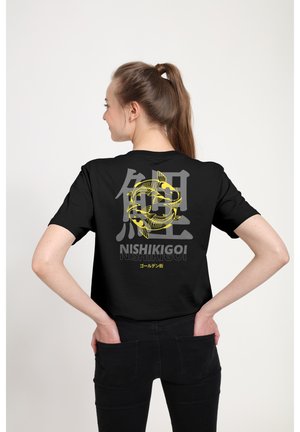 Kvinde med hestehale iført sort t-shirt med gule koi-fisk, japanske tegn og ordet "Nishikigoi" på ryggen.