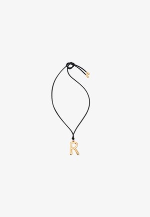 Pendentif en forme de "R" doré sur un collier en cordon noir, avec une finition lisse et une longueur ajustable, orné d'accents dorés aux extrémités du cordon.