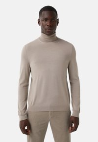 Pull à col roulé beige en tissu tricoté lisse. Il pr�ésente des manches longues, des poignets et un ourlet côtelés, avec une silhouette ajustée.