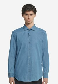 Ljusblå denimskjorta med långa ärmar, knappstängning fram, krage och en enkel knäppt cuff. Slät textur med en regular fit design.