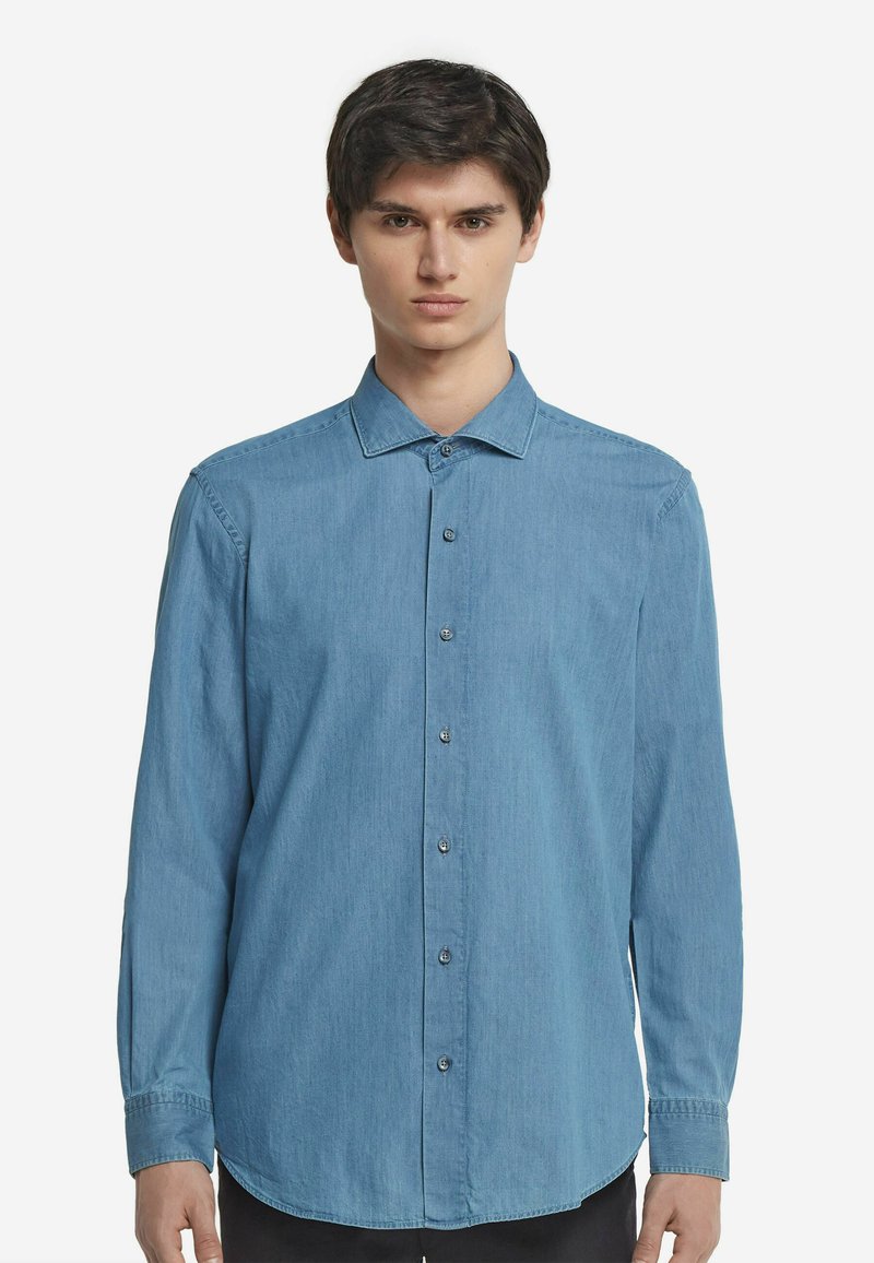 Ljusblå denimskjorta med långa ärmar, knappstängning fram, krage och en enkel knäppt cuff. Slät textur med en regular fit design.