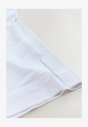 Weißer Baumwollstoff mit glatter Textur, flachen Nähten und einem sanften Bogen am Saum, der ein einfaches und sauberes Design zeigt.