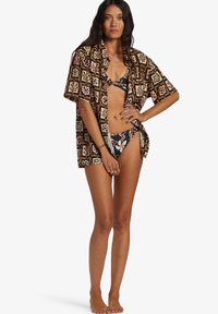 Short-sleeve, oversized shirt in dark brown with a multicolored floral pattern, worn over a bikini. Features a relaxed fit and light fabric.