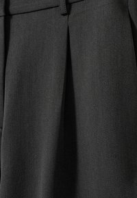 Ciemnoszara, teksturowana tkanina z widocznym skośnym splotem. Zawiera fałdę dla dodatkowej głębi i eleganckiego wyglądu. Odpowiednia na ubrania formalne.