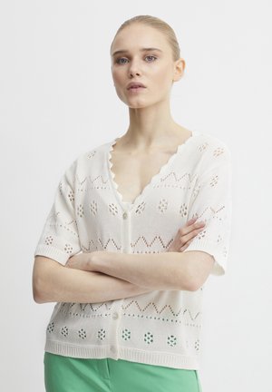 Weißes gestricktes Cardigan mit kurzen Ärmeln, das über einen gewellten Kragen, offene Zickzack- und Punktmuster sowie eine Knopfleiste an der Vorderseite verfügt.