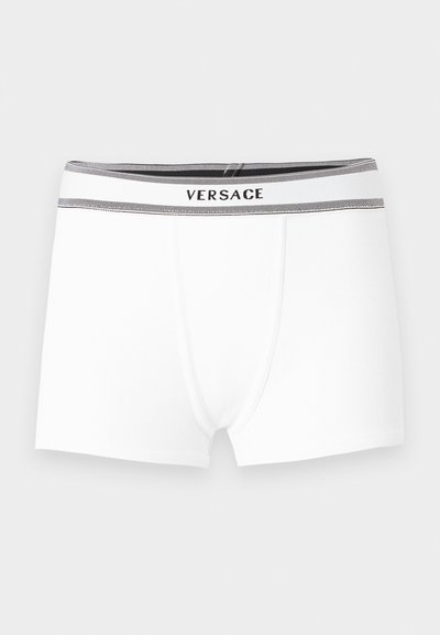Boxers blancs pour hommes avec une ceinture élastique noire et grise portant le nom de la marque Versace.