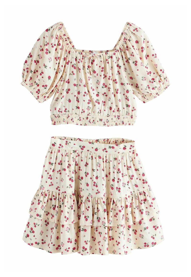 Conjunto de top corto floral y falda de volantes en tela color crema, con patrones de flores rosas, mangas con volantes elásticos y cinturilla elasticada.