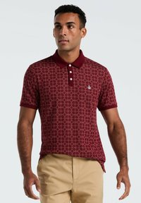 Bordeaux polo shirt met een geometrisch patroon, korte mouwen en een kraag met drie knopen. Klein logo op de linkerborst.