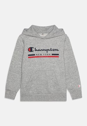 Hellgrauer Champion-Hoodie mit Fronttasche, navyblauem und rotem Logo-Text "Champion New York Since 1919" sowie kleinem Logo auf dem linken Ärmel.