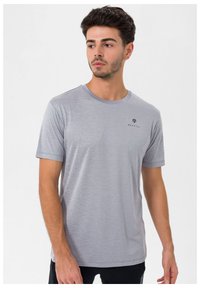 Grå kortærmet T-shirt lavet af blødt stof, med rund halsudskæring og et lille sort logo på venstre bryst.