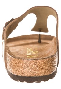 Brun kork sandale med en formet fodseng, justerbar strop, gummiydersål og tekstureret inderside for greb. To huller for struktur.