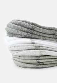 Set di calzini in varie tonalità di grigio e bianco, con una morbida texture a maglia caratterizzata da sottili variazioni di colore e bordi arrotolati.