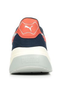 Sneaker blu navy con tomaia in suede, dettagli arancioni e suola in gomma. Presenta una intersuola grigia testurizzata e un logo Puma prominente.