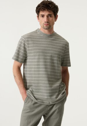 Graues kurzärmeliges T-Shirt mit einem strukturierten Streifenmuster. Rundhalsausschnitt, lockere Passform, kombiniert mit hellgrauen Hosen.