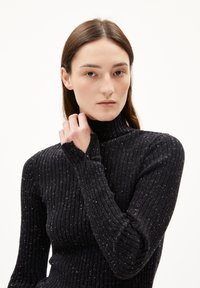 Maglione a collo alto nero a coste con un motivo testurizzato e una vestibilità comoda. Presenta un dettaglio con bottone sul polsino e leggere venature in tutto il capo.