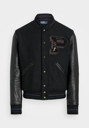 Veste universitaire noire avec corps en laine et manches en cuir. Caractéristiques : poignets côtelés, fermeture éclair à l'avant et détail de logo brodé sur la poitrine.
