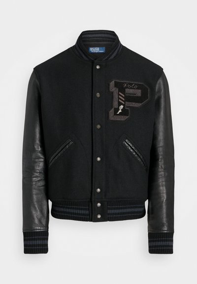 Black varsity jacket with wool body and leather sleeves. Features ribbed cuffs, a zippered front, and embroidered logo detail on the chest.