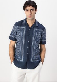Navy short-sleeve button-up shirt with intricate light blue geometric patterns, featuring a relaxed collar and a smooth fabric texture.