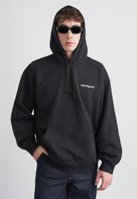 Sudadera con capucha negra hecha de tela suave con un bolsillo canguro y capucha con cordón. Presenta el logo "carhartt" bordado en blanco en el pecho.