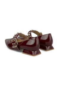 Chaussures à talons bas en cuir verni bordeaux avec des bouts pointus, larges sangles avec boucles dorées et embellissements en clous, semelles beiges.