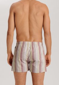 Pantaloni boxer a righe con una pallet di colori pastello che include rosa, giallo e bianco, dotati di una vita elastica e di una vestibilità comoda.