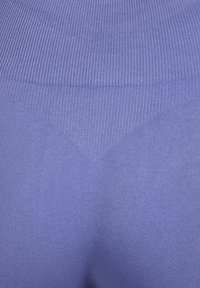 Leggings viola senza cuciture con texture a coste in vita e finitura liscia sulla gamba, che crea una silhouette aderente.