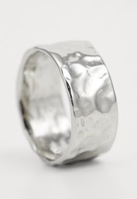 Sølvring med en hamret tekstur, med en glatt, bred ring og polert finish som reflekterer lys med subtile feil.