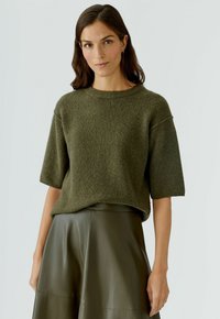 Olivgrüner gestrickter Pullover mit kurzen Ärmeln, strukturierter Stoff, runder Ausschnitt, kombiniert mit einem passenden hoch taillierten Ledrock.