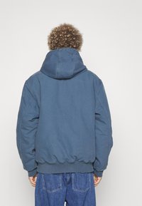 Blauwe oversized hoodie met een textuurafwerking, capuchon met trekkoord en elastische manchetten. Gepaard met losse denim broek.