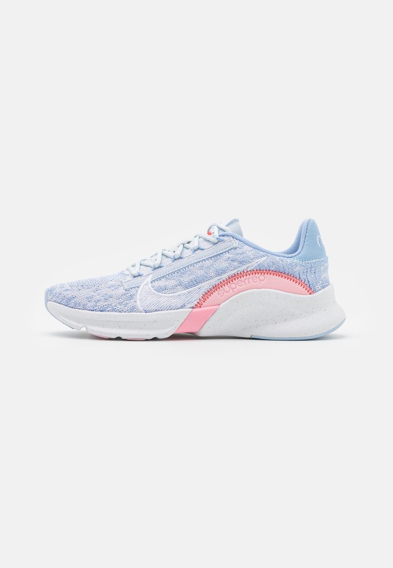 Chaussure de sport tricotée bleu clair avec logo swoosh blanc, accents roses et semelle blanche épaisse vue de côté sur fond blanc.