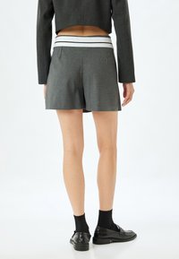 Pantaloni corti grigi su misura con una cintura a strisce bianco e nero, caratterizzati da una linea elegante e un tessuto texturizzato, mostrati sul retro.