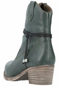 Bota de tobillo de cuero verde con punta redondeada, tacón texturizado y detalle lateral de cordones. Presenta un tacón de madera apilada para mayor estilo.