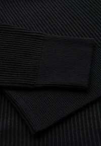 Tessuto di maglione nero con texture a coste, caratterizzato da un ampio polsino a coste. Il materiale appare morbido e flessibile, strutturato per una vestibilità aderente.