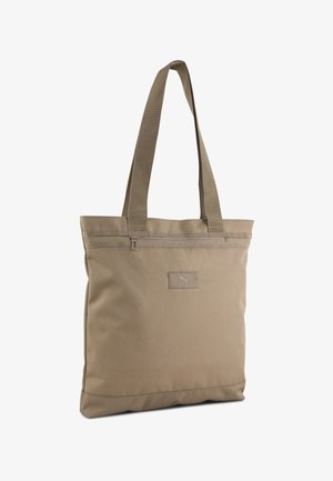 Beige rectangular tote bag with long straps, top zipper pocket, and small Puma logo patch on front center.
