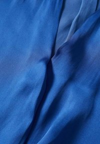 Tissu opaque bleu avec une texture lisse et légèrement brillante, présentant des drapés doux et des plis délicats. Idéal pour les vêtements ou les accessoires.