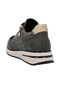 Sneaker vert avec des panneaux en tissu texturé, des accents dorés et une fermeture éclair sur le côté. Il dispose d'une semelle rembourrée et d'une semelle extérieure noire contrastante.