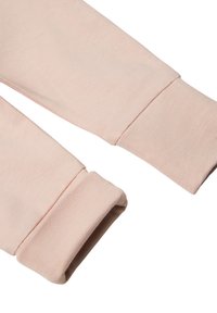 Ljusrosa bomullsmuddar med ribbade ärmslut, med en slät yta och en vikning vid mudden.