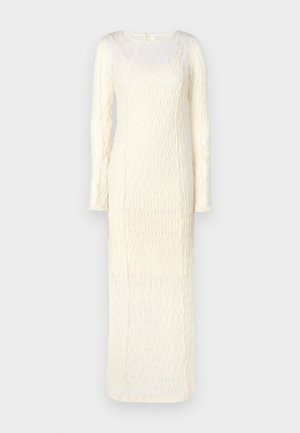 Hosszú ujjú, padlót érő krémszínű ruha texturált mintával és négyzet alakú nyakkivágással. Hátul megkötős záródással rendelkezik.