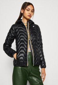 Giacca nera trapuntata con chiusura lampo frontale, cappuccio e tasche; presenta una texture lucida e un interno a righe in contrasto.