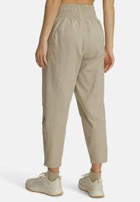 Bežid cropped joggers, mille elastse vöökoht, küljetaskud ja sile tekstuur. Kombineeritud heledate tossudega.