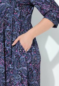 Vestido marinero con intrincado estampado de paisley en azul y rosa, que presenta una cintura fruncida y un bolsillo lateral, mostrando una tela suave y un diseño casual.