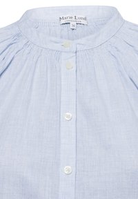Camicia button-up azzurro chiaro con scollo arricciato, caratterizzata da bottoni bianchi e un tessuto liscio e strutturato. Etichetta leggere "Marie Lund, Copenhagen, 36."