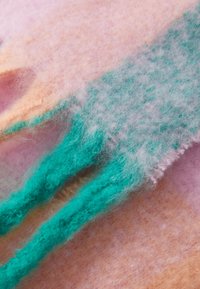 Multifarvet filtstof med en blanding af bløde rosa, fersken og teal nuancer, med en fuzzy tekstur og lagdelt udseende.