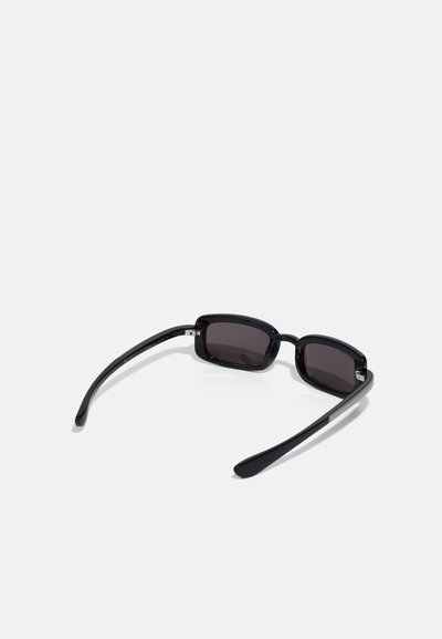 Lunettes de soleil noires rectangulaires avec verres teintés, cadre en plastique lisse et branches fines. Présente des accents métalliques près des charnières.