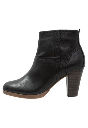 Bottine en cuir noir avec talon bloc empilé et bout arrondi, dotée d'une languette à l'arrière et de coutures visibles.