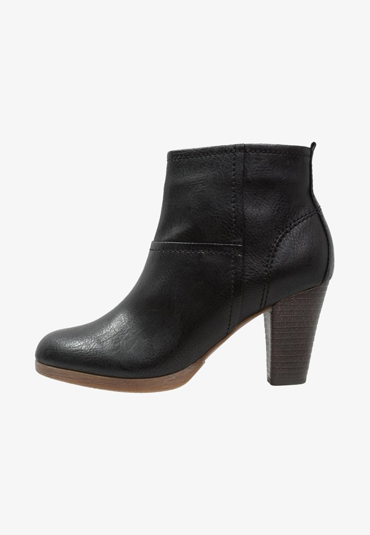 Bottine en cuir noir avec talon bloc empilé et bout arrondi, dotée d'une languette à l'arrière et de coutures visibles.