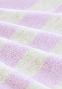 Textil mit einer sanften Textur, ausgestattet mit einem karrierten Muster aus helllila und cremefarbenen Quadraten, gefaltet, um Tiefe und Detail zu zeigen.
