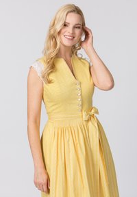 Gelbes Kleid mit kurzen Spitzenärmeln, einem V-Ausschnitt und Knopfverschluss. Es hat eine Gummizug-Taillierung und eine gebundene Schleife an der Seite.