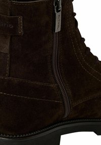 Braune Wildleder-Ankle-Boots mit einem seitlichen Reißverschluss, kontrastierenden Nähten und einer schwarzen Gummisohle mit strukturiertem Rand.